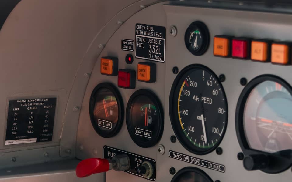 Prim-plan cu bordul unui avion de școală: indicatoare de combustibil, o fișă de etalonare a combustibilului și un vitezometru.